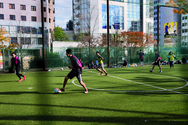Football Pitch in the busy and fashionable Shibuya, central district of Tokyo. Young men and women playing on a Saturday afternoon. The access to this football field is reserved to the inhabitants of Shibuya district who can rent it for JPY 7000 per hour. Decembre 2015.